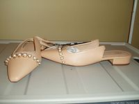 Pair of light tan ZARA women's shoes size 8 with pearl embellished strap and low block heels shown from side angle