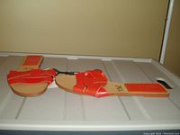 Side view of orange ZARA slides showing straps and flat sole, on a plastic surface.