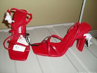 Pair of bright red women's strappy heeled sandals, size 8, new with tags attached, displayed from side and top views.