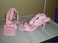 Photo of pink ZARA high heel ankle wrap shoes with circular details on straps, on white surface against beige background.