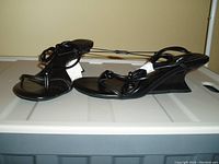 Side view of black ZARA wedge shoes with ankle wrap straps on neutral background.