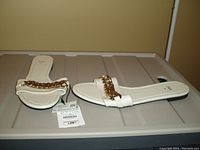 Single pair of beige ZARA slides with a gold chain detail and attached price tag indicating size 8.