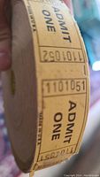 Close-up photo of the Admit One ticket roll showing printed numbers and text Admit One.