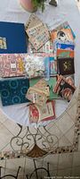 Overview of all 16 different stamp albums stacked and laid out on a table along with loose cards and bags with stamps