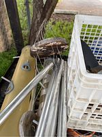 Metal garden poles, parts of birdhouse and white plastic crate on grass background.
