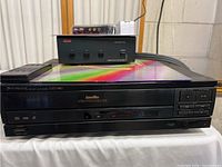 Front view of the Pioneer CLD-980 CD LaserDisc Player with remote control on top, showing unit details and power button.