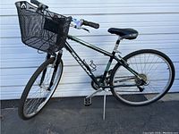 Full side view of the green Schwinn Voyager bike with front basket, showing frame, wheels, pedals, and seat