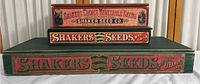 Front view of three stacked vintage wooden Shaker seed boxes showing different sizes and branding.