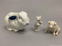 Front view of all three porcelain figurines: Tiffany & Co. bunny coin bank with blue spots, Belleek pig, and Hutschenreuther bear.