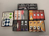 Full overview of all golf ball boxes arranged in open box showing variety of brands and packaging.