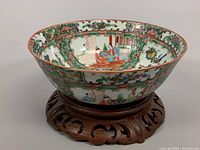 Angled side view of the bowl displayed on the wooden base showing the hand painted exterior and base design.