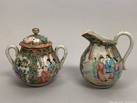 Front view of covered sugar bowl and creamer jug showing hand-painted Rose Medallion motifs and dual handles on sugar bowl with lid finial.