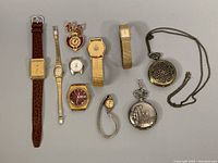 Full lot overview showing various vintage wristwatches, pendant watch, and two pocket watches with chains.