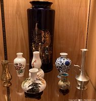 Group shot of all seven Asian single bud vases displayed together showing varied materials and designs
