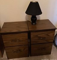 Front view of two nightstand cabinets with lamp on top, drawers closed