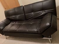 Faux leather sleeper couch upright showing padded armrests and seat cushions