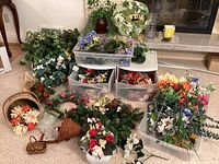 Lot overview with artificial flowers in multiple Rubbermaid containers and scattered wicker baskets