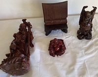 Four Japanese figurines on white cloth, showing carved elder, cast resin Buddhas, and wooden temple