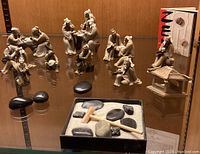 All 13 clay Mudmen figurines with Zen garden tray and wooden rake visible in display case.