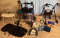 Full view of the medical supply lot showing walkers, shower stools, massager chair cover, heating pad, and boxes of medical devices.
