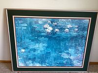 Framed print showing a blue pond with water lilies in Monet impressionist style, double matted with green and white mats.