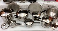 Photo showing an assortment of pots, pans, strainers, and lids with some brand variety visible.