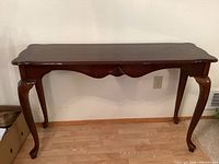 Full view of sofa table from the front showing carved shell accent and cabriole legs.