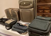 Set of six soft shell luggage pieces of different sizes arranged on floor showing carry-on suitcases and small duffel bags