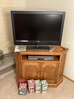 Sony 32 inch LCD TV on wooden corner cabinet with Samsung DVD/VHS player and two remotes visible