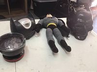 Photo of Batman doll, Batman mask, and two electronic devices placed on a table.