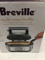 Box of Breville waffle maker highlighting 'No-mess Waffle' branding and image showing waffle being removed with spatula.