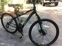 Side view of Huffy mountain bike with visible brand markings, front suspension fork, disc brakes, and tires needing air.