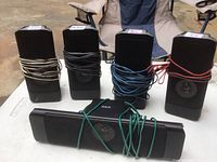Five RCA speakers displayed outdoors. Four vertically oriented rectangular speakers and one longer horizontal center speaker are shown. Wires wrapped around each speaker.
