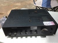 Front and top angled view of Radio Shack amplifier showing control knobs, power meter, ventilation slots, and power button in untested condition.