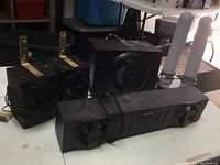 Sharper Image black speaker set including two satellite speakers with metal mounting brackets, central horizontal speaker, subwoofer, and two white wireless antennas.