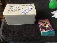 Cardboard box labeled 'Football Cards Super Set 333 Cards' and stack of football cards featuring Shannon Sharpe on top
