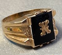 Three-quarter front view showing rectangular black onyx face with raised scripted 'K' and fluted shoulders