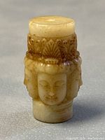 Front view showing one of four Buddha faces with detailed facial features and headdress pattern