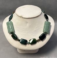 Front view of jade necklace displayed on white bust