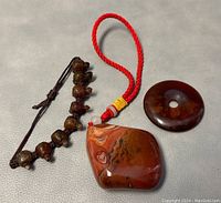 Photo showing beaded jade turtle bracelet with multiple turtle-shaped beads, large polished agate pendant with red cord, and round agate donut pendant.