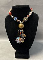 Front view of the full necklace showcasing colorful mixed beads and the cloisonné elephant pendant hanging below a large brass bead.