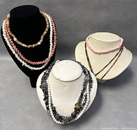 Five assorted beaded necklaces displayed on three busts, showing variety of beads and semi-precious stones
