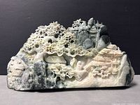 Front view of the carved Dushan jade sculpture showing intricate landscape scene with trees, rocks, buildings, and figures.