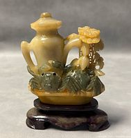 Front view of Chinese jade sculpture showing two crabs under a vase with floral decoration on a wooden stand.