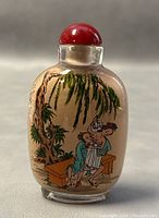 Front view of snuff bottle showing intimate scene with couple under a willow tree sitting on a bench.