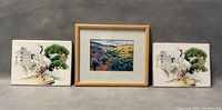 Photo showing framed watercolour painting in center with two ceramic tiles featuring crane artwork placed on each side.