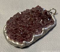 Top angled view of raw amethyst pendant showing the crystalline structure and silver-tone setting with bail attachment.