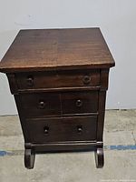 Front view of antique wooden dresser showing three drawers and wear on top surface.
