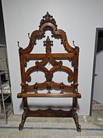 Front view showing overall carved crest, coat hooks and umbrella rail