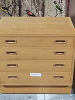 Front view of a light wood four drawer dresser with recessed handles and natural wood grain visible.
